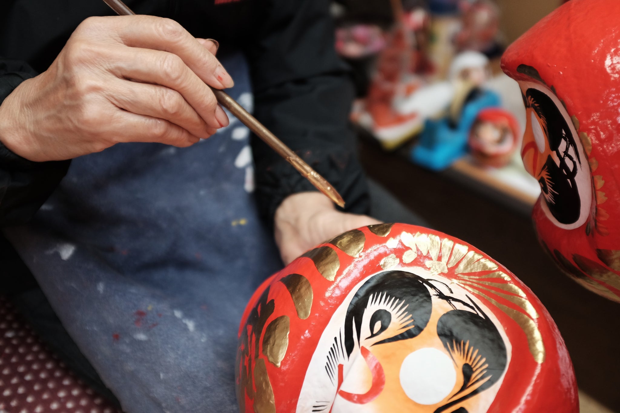 japanese craftsman painting daruma dolls by hand